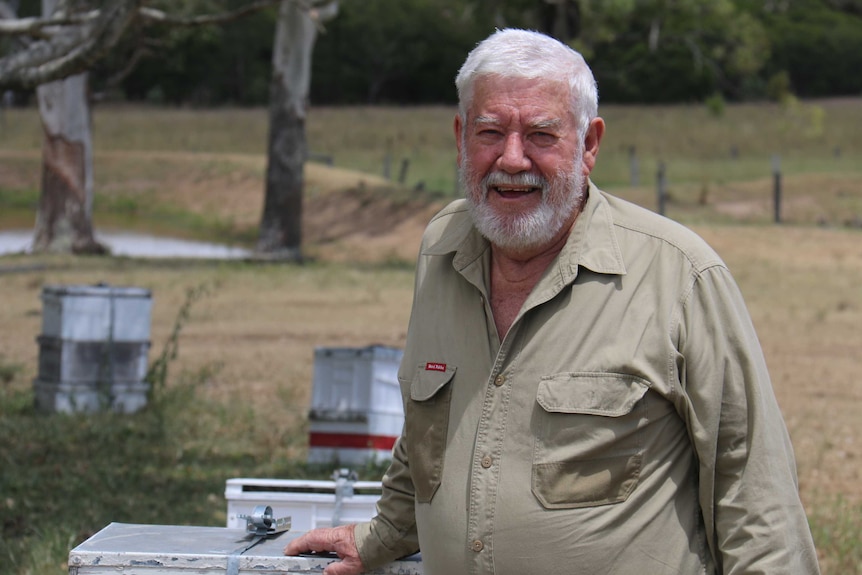 Trevor Weatherhead smiles as he rests his hand on a box in a yard.