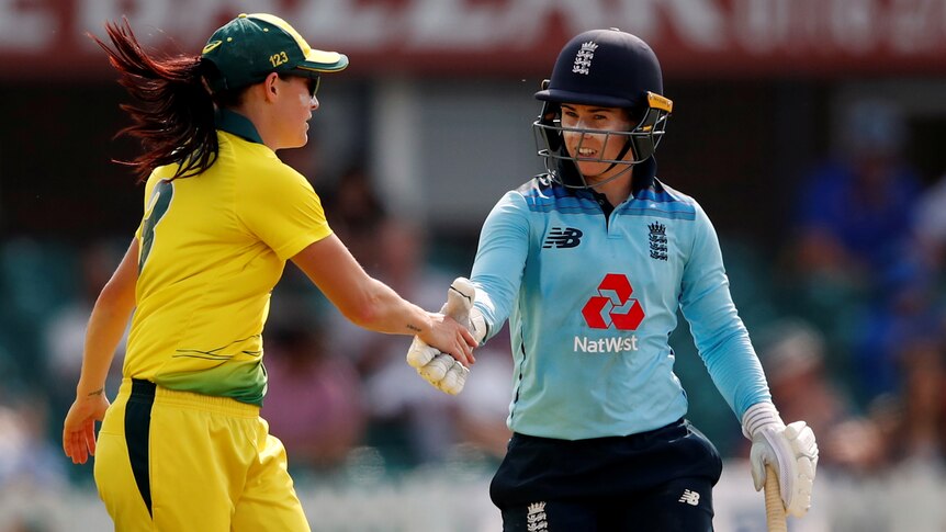 Megan Schutt, wearing yellow, shakes hands with Tammy Beaumont, wearing blue