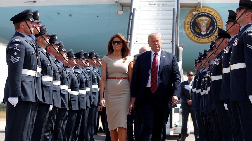 US President Donald Trump and his wife Melania walk through a military guard