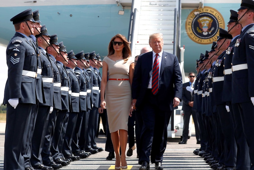 US President Donald Trump and his wife Melania walk through a military guard