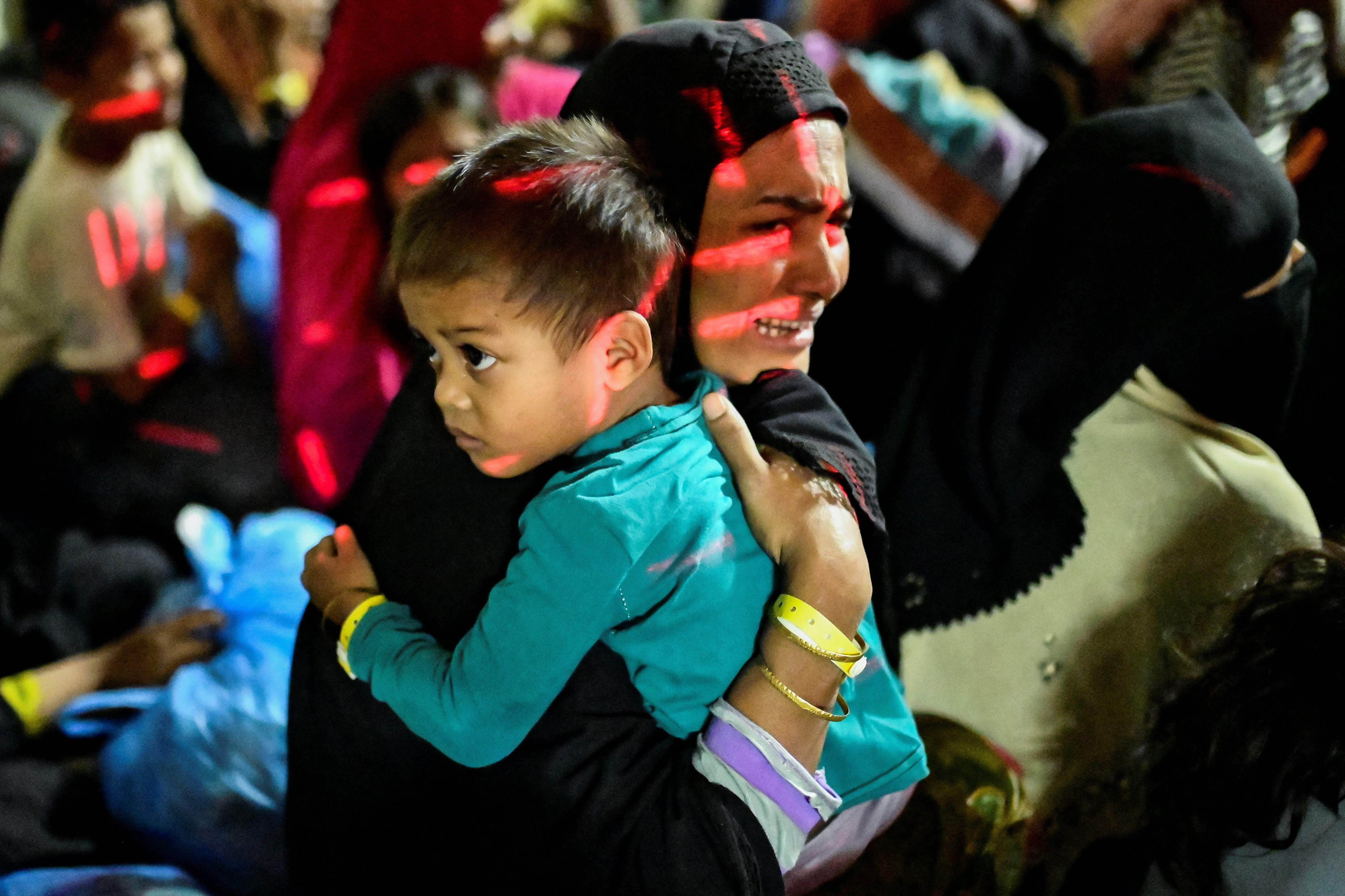 A Rohingya Muslim woman wearing hijab cries while holding her child close