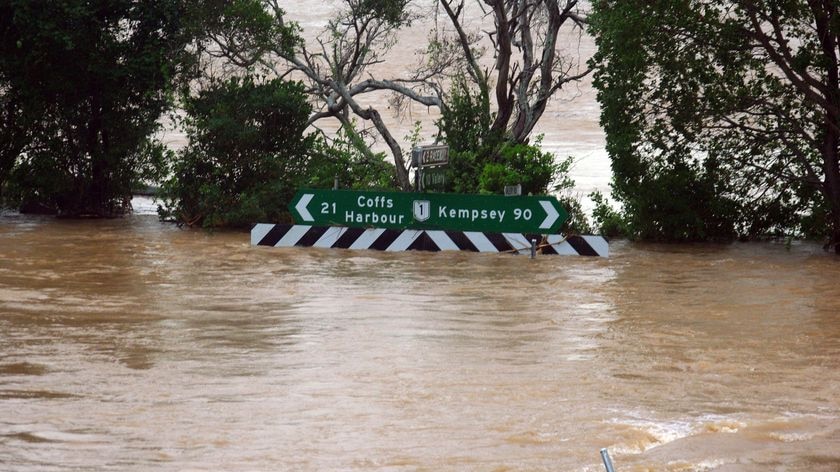 Floodwaters reach a road sign pointing to Coffs Harbour on the Valery Road intersection