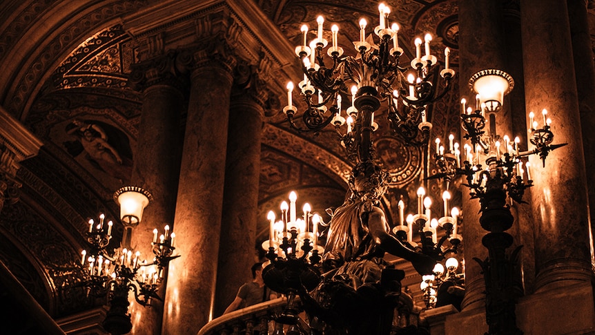 An ornate brass candelabra sitting on a stairway banister.