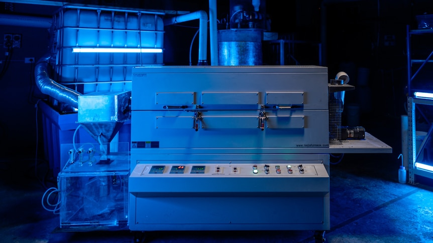 Machinery pictured in a blue light. There are buttons to press on the machine.