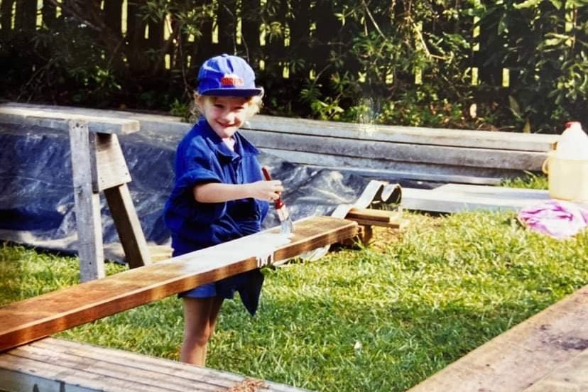 Little girl painting piece of timber