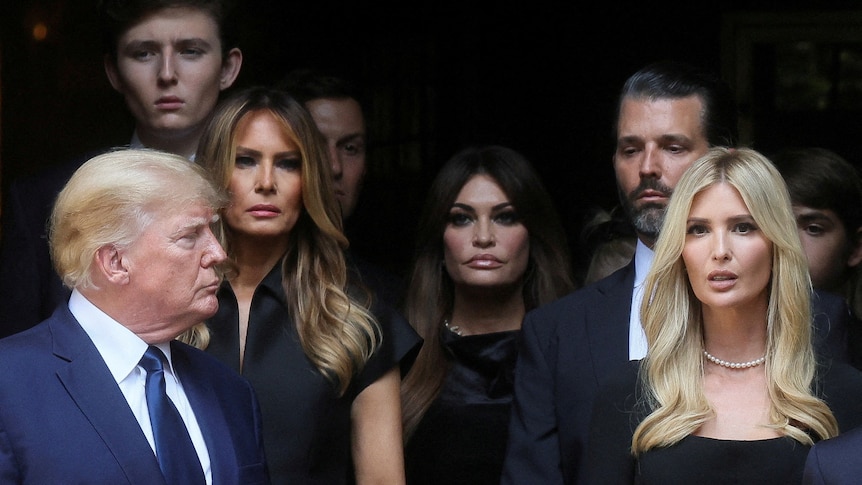 Donald Trump Ivanka, Melania, Barron, and Don Jr stand together looking solemn 