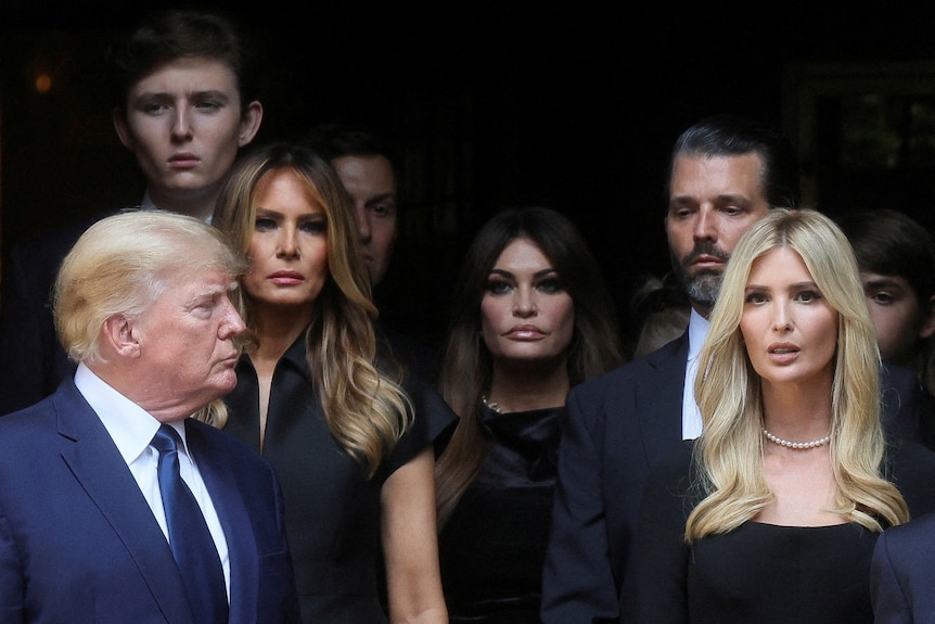 Donald Trump Ivanka, Melania, Barron, and Don Jr stand together looking solemn 