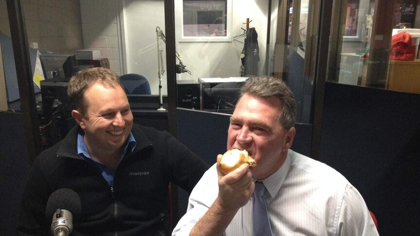 Devonport Mayor Steve Martin taking a big bite into a raw onion in an ABC radio studio in Burnie, north-west Tasmania.