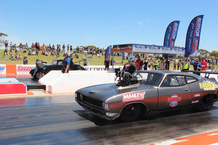 A grey racing car on a drag strip.