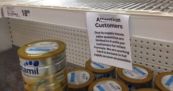 A sign on supermarket on a near empty supermarket shelf restricts the sale of baby formula to 4 cans.