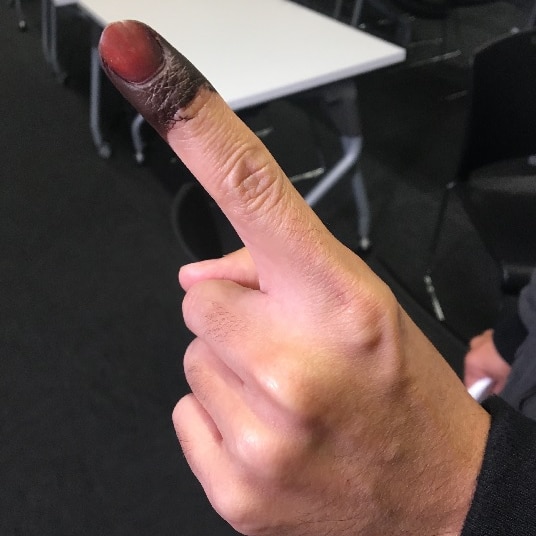 An index finger with black ink on the end of it