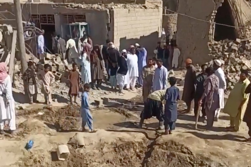 People gather near rubble in the aftermath of Pakistan's military strike on an Iranian village.