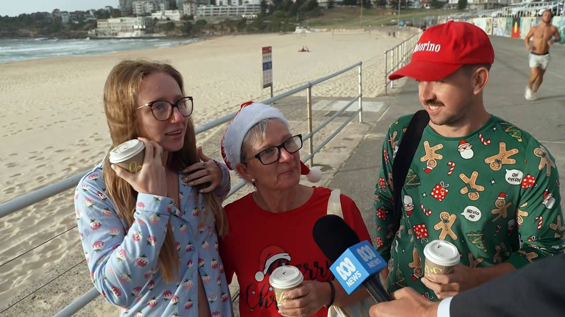 Uma família de três pessoas no calçadão de Bondi Beach conversando com a mídia.