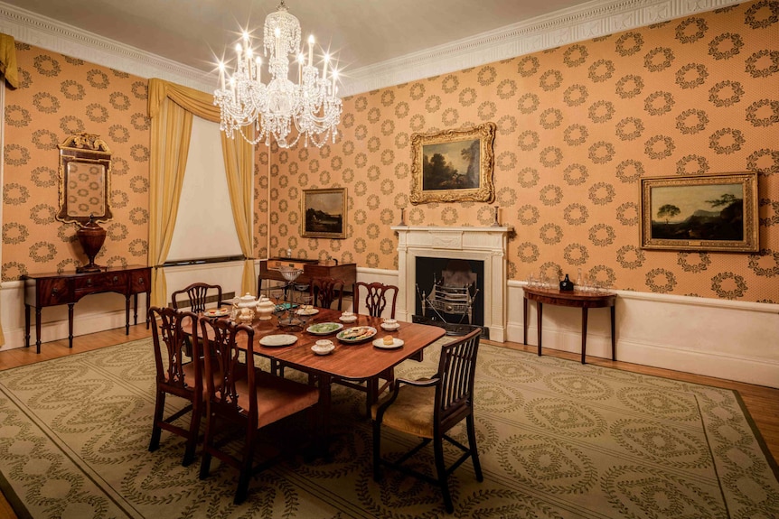 A chandelier hangs above a dining table and chairs.