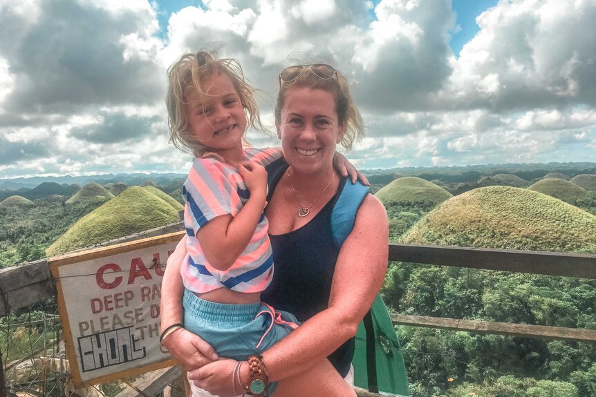 Photo of mother holding daughter on her hip in front of hills in Bohol, Philippines.