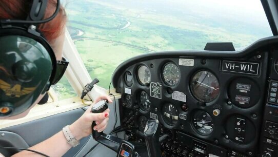 Suicide survivor Hayley Purdon in the cockpit of a plane, flying over a field.