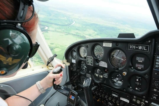 Suicide survivor Hayley Purdon in the cockpit of a plane, flying over a field.