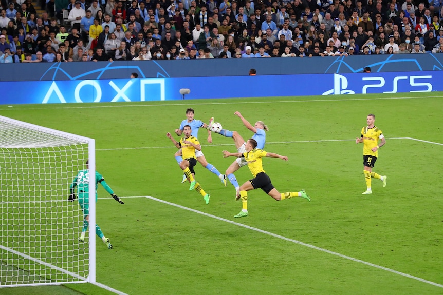 Erling Haaland of Manchester City connects with a jumping kick at a soccer ball during a Champions League game against Dortmund.