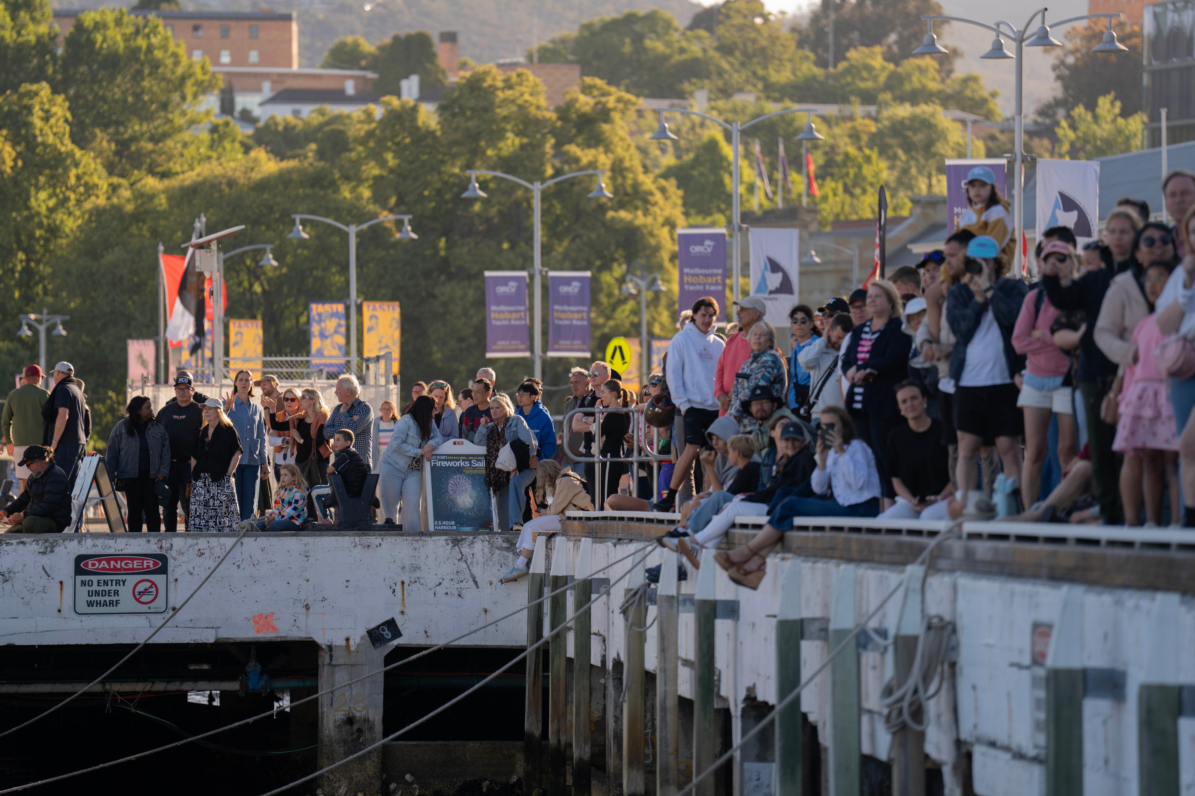 Crowds watch the Sydney Hobart yacht race from Hobart's waterfront.