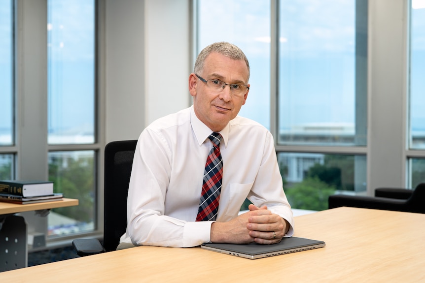 Le commissaire de l'ICAC des NT, Michael Riches, assis à un bureau dans son bureau.