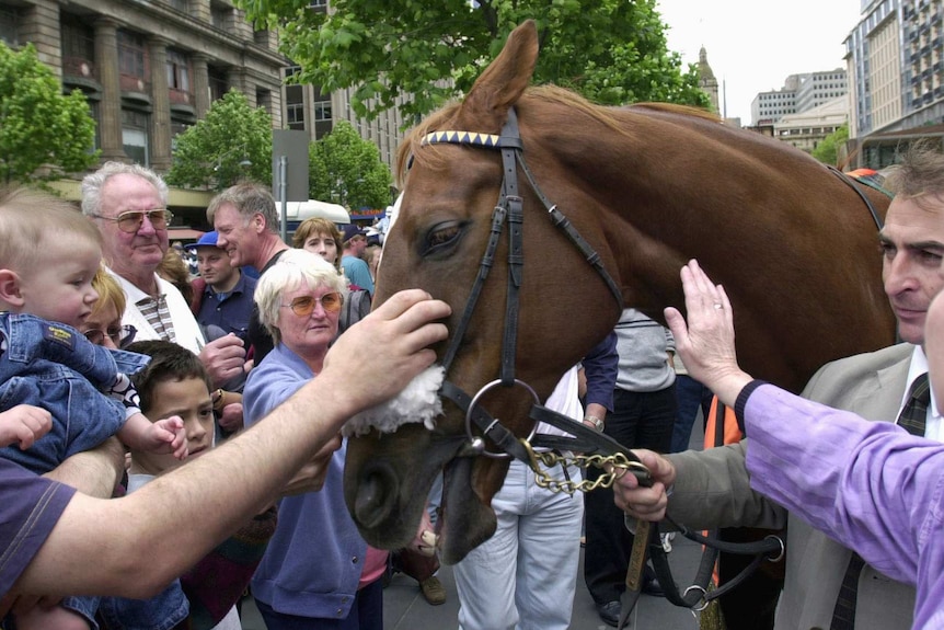 People gather around 1993 Melbourne Cup winner Vintage Crop after the 2000 Melbourne Cup parade.