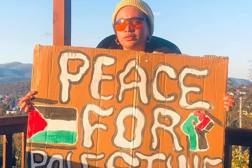 Australian activist Priya Vunaki Singh holds a hand-painted sign with the words 'Peace for Palestine'.