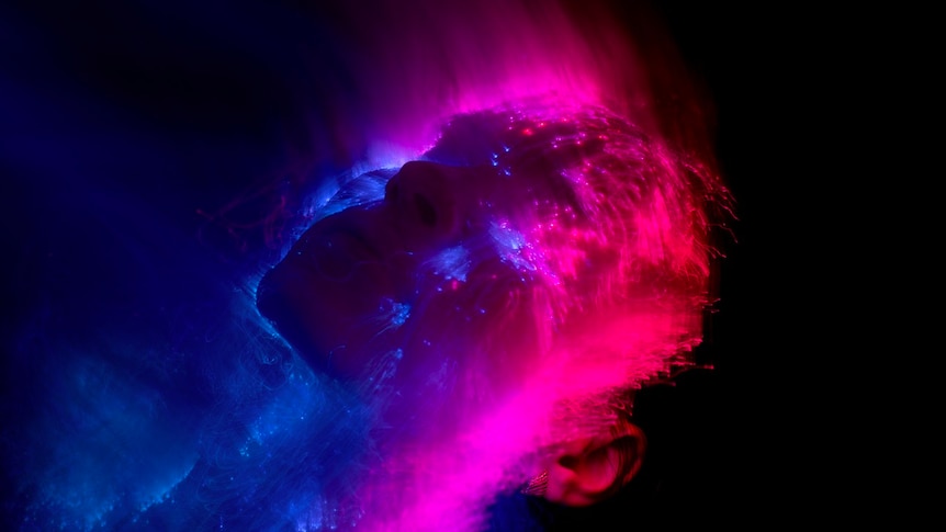 A stylised picture of a woman's face made from high-contrast blue and magenta points of light