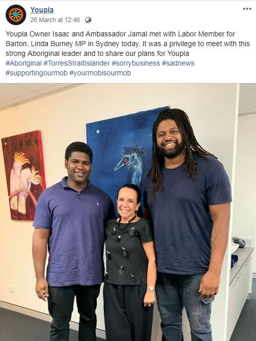 A screenshot of a Facebook post featuring two men and a woman standing against a wall with a painting of an emu in background.