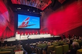 A red stage with Qantas logo on projector 