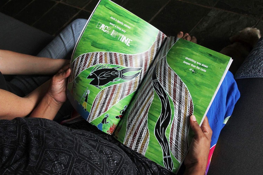 hands hold a picture book with a forest image