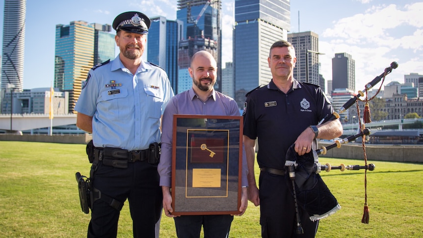 Policemen standing in line holding a framed key and bagpipes.