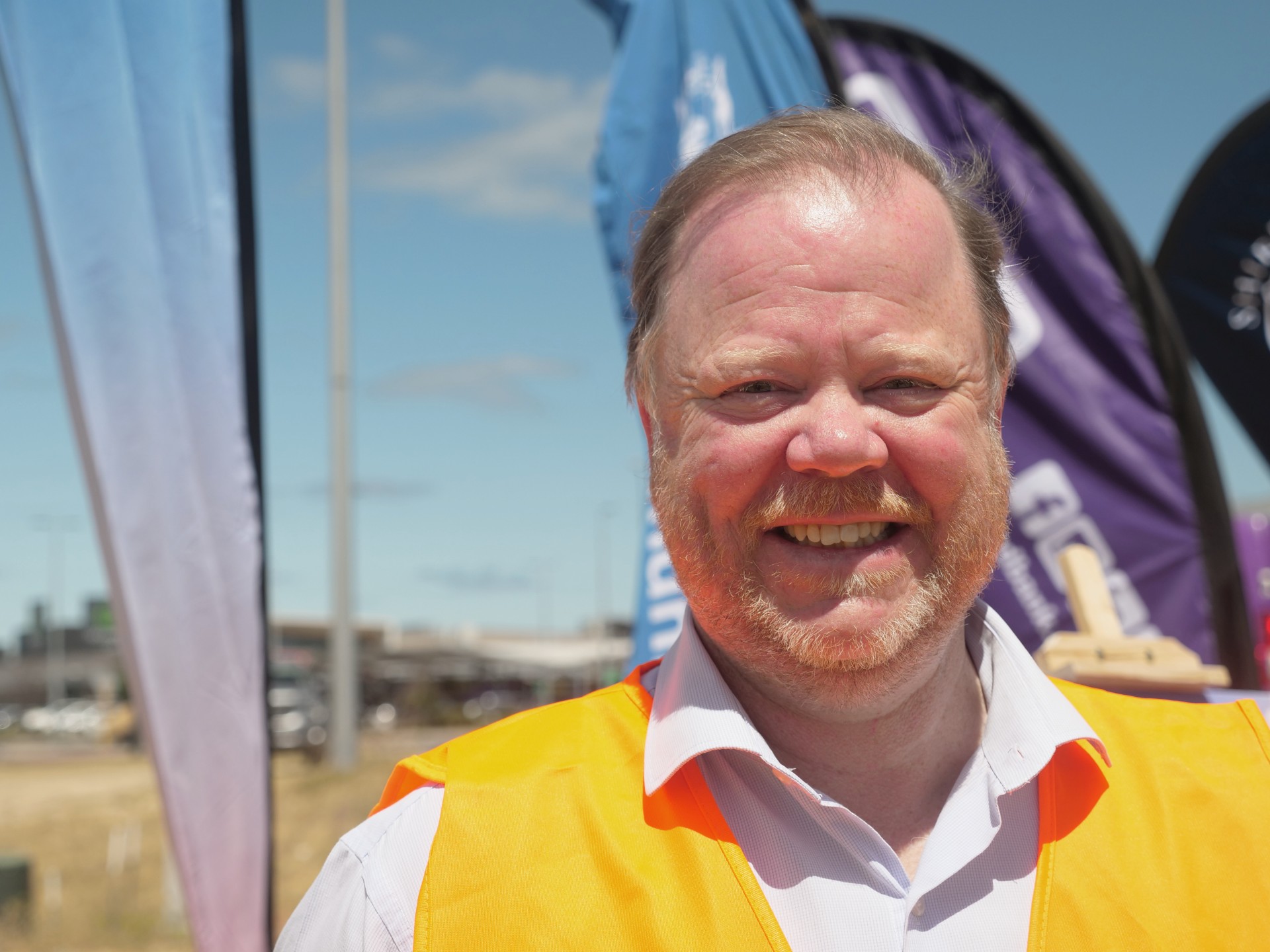 Una imagen de un hombre sonriente con un chaleco naranja.