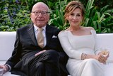Rupert Murdoch and Elena Zhukova sit on a white couch in a garden, holding drinks