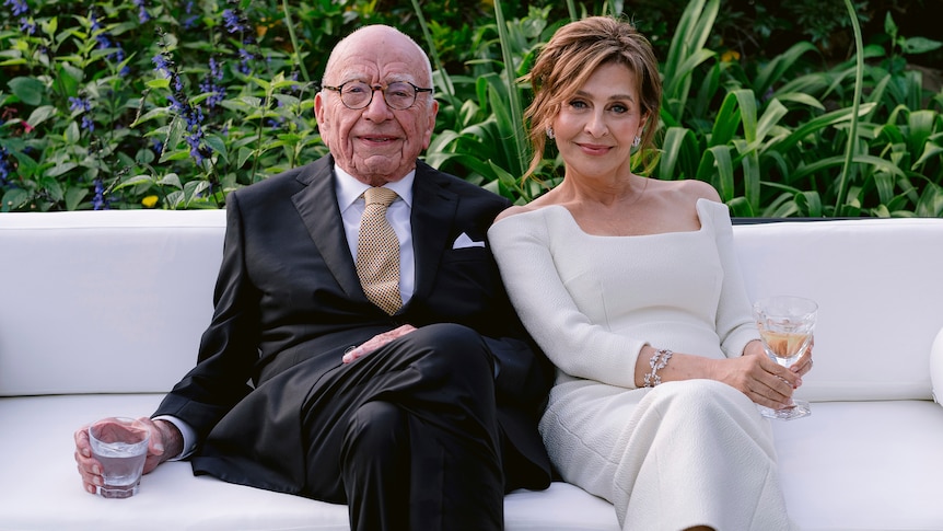 Rupert Murdoch and Elena Zhukova sit on a white couch in a garden, holding drinks