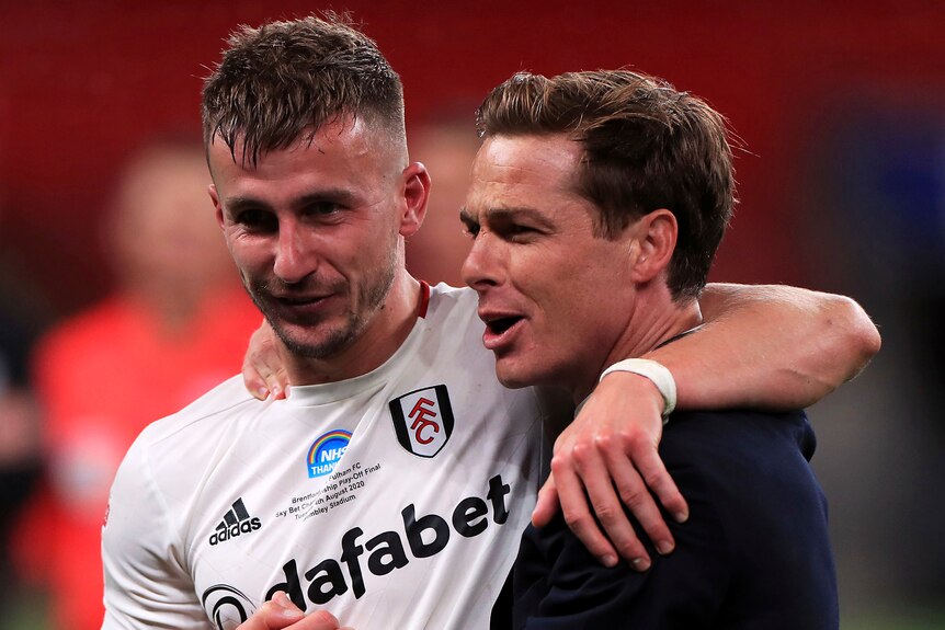 Scott Parker, wearing a shit, and Joe Bryan, wearing a white shirt, hug.