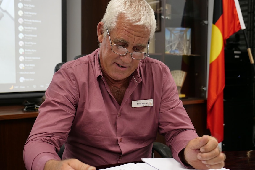 a man studies a document at an official looking desk