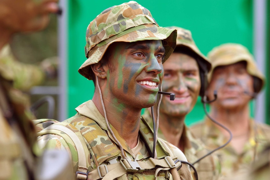 Private Michael Mani and two other reservists wearing fatigues and camouflage face paint.