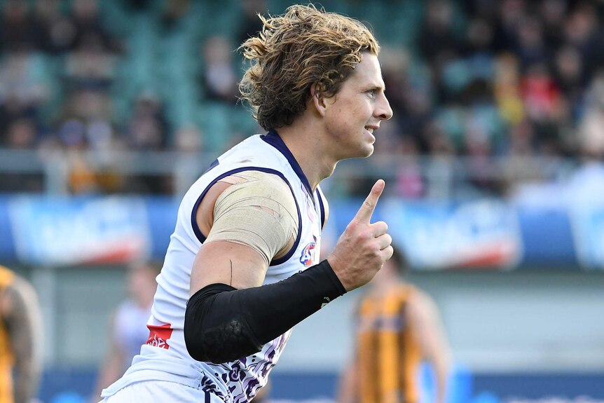 A side-on shot of Dockers captain Nat Fyfe celebrating a goal during an AFL game with his finger raised.