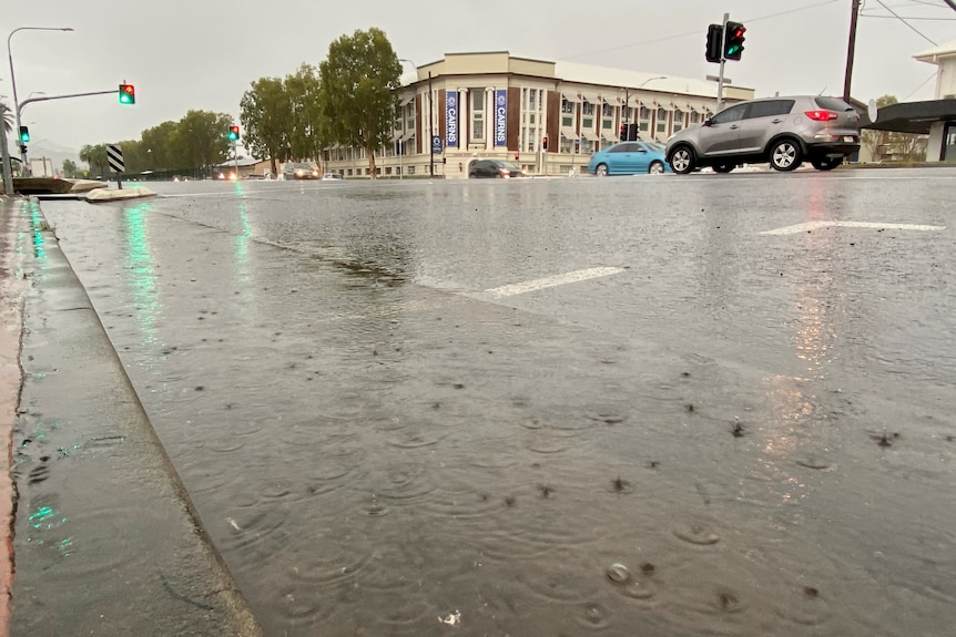 Cars drive down the main street of a wet Cairns