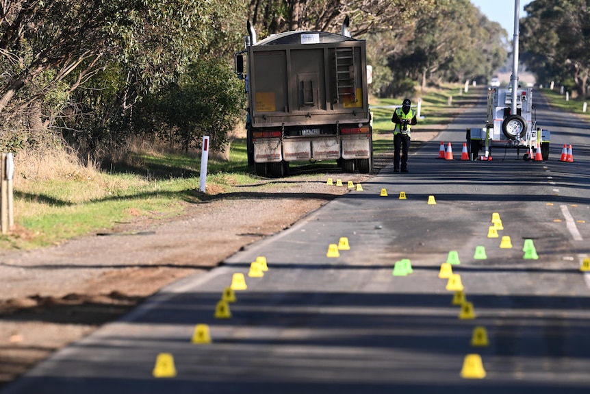 A truck on a road with markers and police.