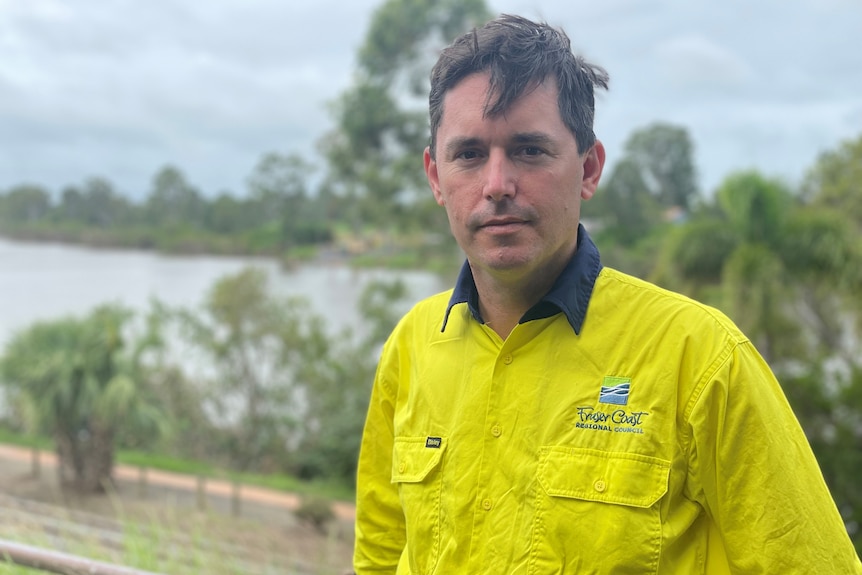 Man in high visibility shit stands over river 