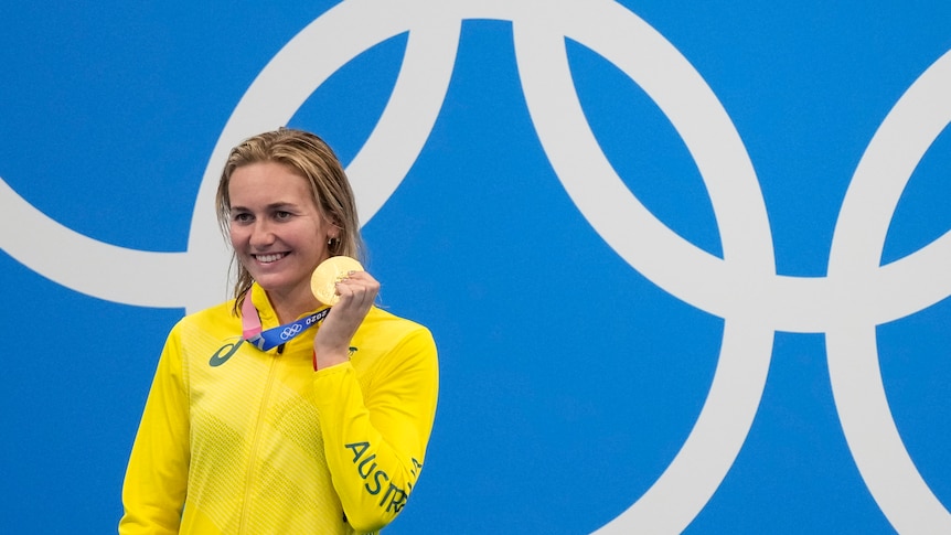 Ariarne Titmus stands with her gold medal after winning the women's 200m freestyle final at the Tokyo Olympics.