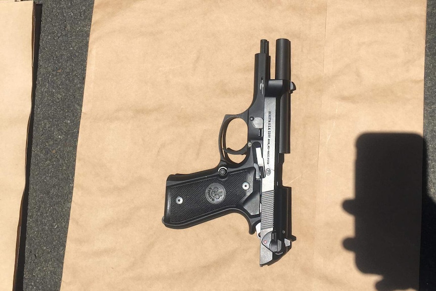 A black gun photographed on a brown paper bag.