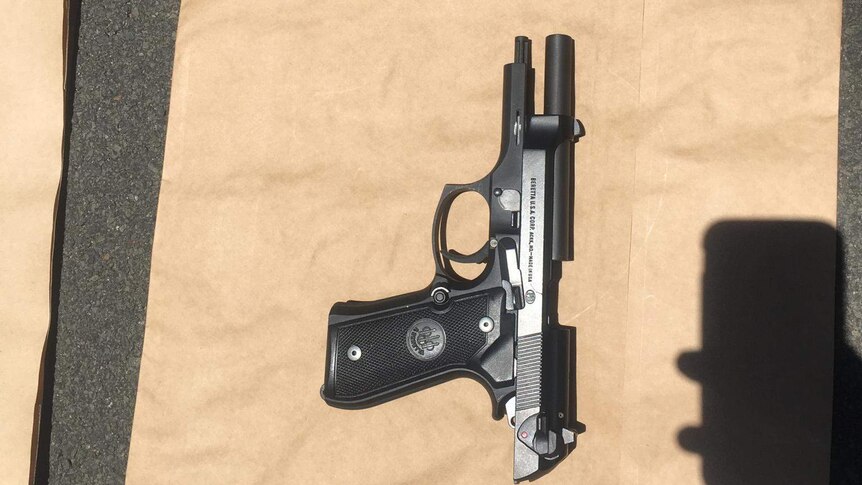 A black gun photographed on a brown paper bag.