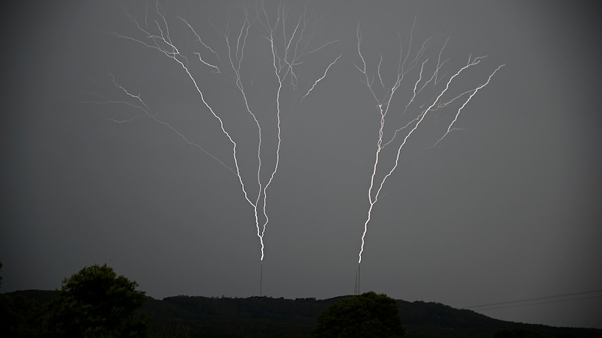 Lightning streaks into the sky, seemingly out of two silver towers on the horizon.