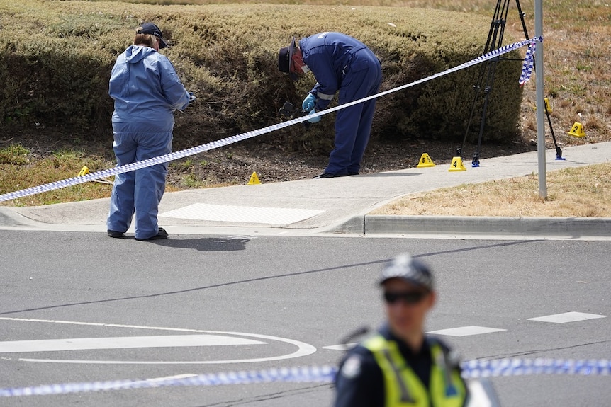 Police forensic specialists can be seen working a crime scene behind police tape.