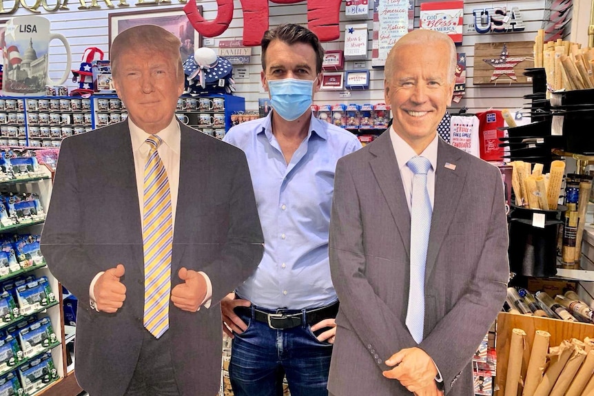 Michael Rowland poses with cardboard cut-outs of Donald Trump and Joe Biden.