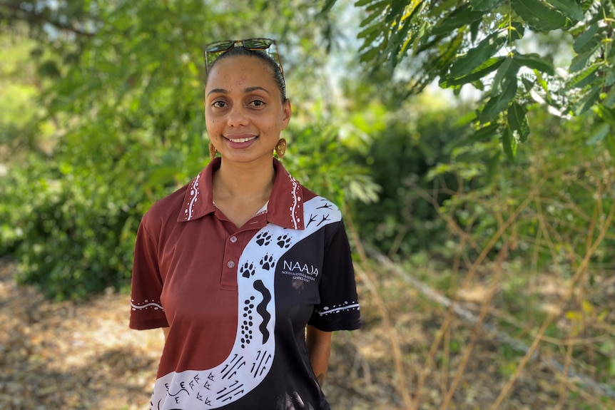 A young woman wearing a NAAJA branded shirt.