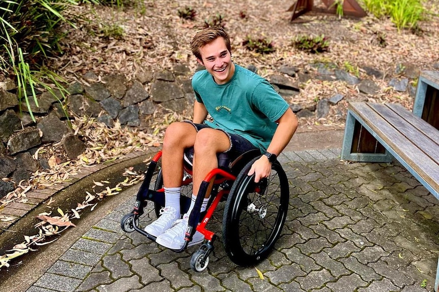 A man in a wheelchair pictured pictured smiling outdoors.