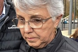 A grey-haired woman wearing glasses and a black puffer jacket next to a white-haired man in a black puffer jacket.